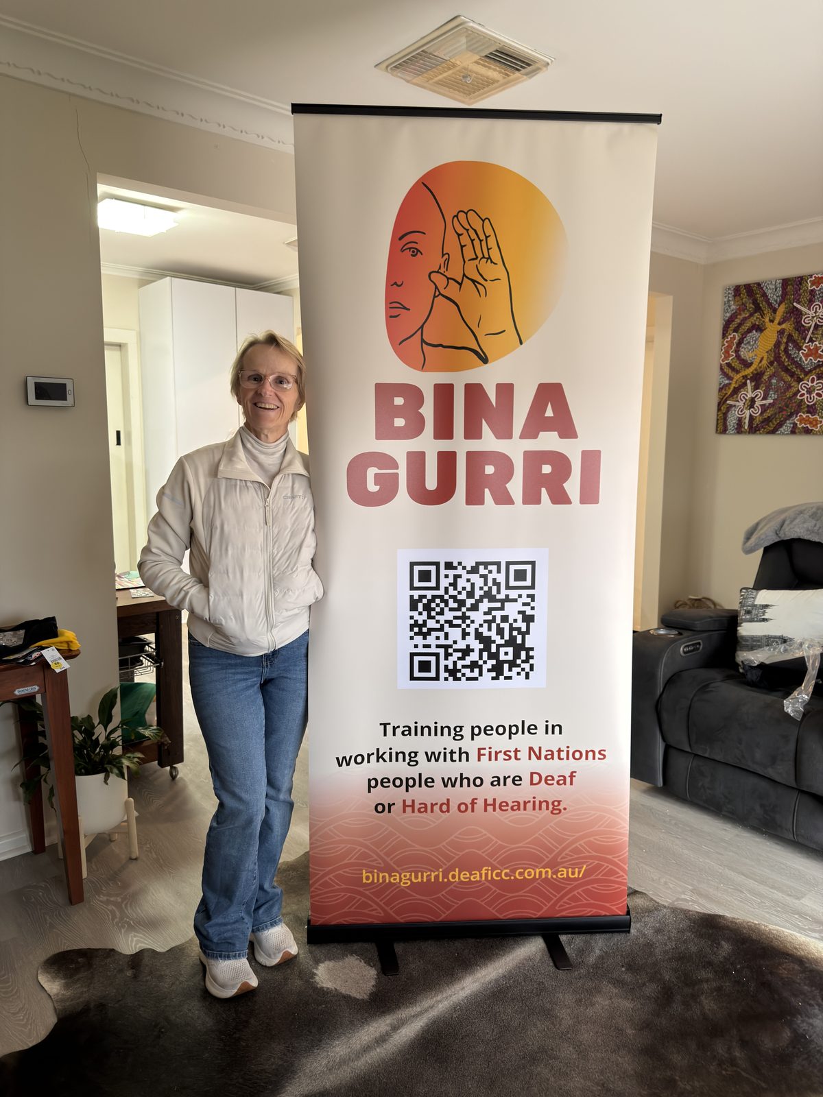 Jody standing beside a Bina Gurri banner